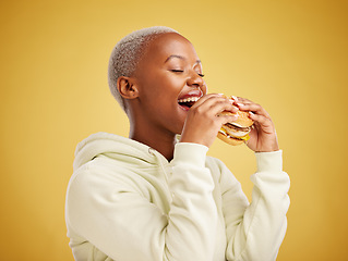 Image showing Hamburger, eating and happy woman or student on a studio, yellow background for restaurant promotion or deal. Hungry and excited african person or customer experience with fast food and burger bite