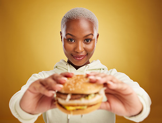 Image showing Burger, offer and portrait of woman or student on studio yellow background in restaurant promotion or deal. Giving, eating and young african person for customer experience with fast food or hamburger