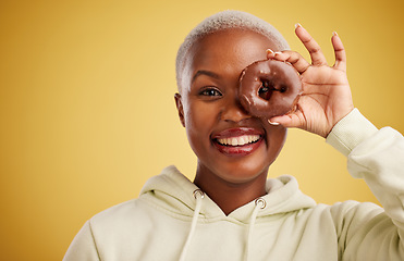 Image showing Portrait, chocolate and donut with a black woman in studio on a gold background for candy or unhealthy eating. Eye, food or baking with an excited young female person holding sweet pastry for dessert