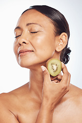 Image showing Relax, beauty or mature woman with kiwi for healthy detox, skincare or facial treatment routine in studio. Spa, face or senior model with wellness, self love or fruit isolated on white background