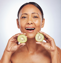 Image showing Face, excited and mature woman with kiwi in studio isolated on a white background. Portrait, fruit and natural model with food for nutrition, skincare and diet for vitamin c, anti aging and health.