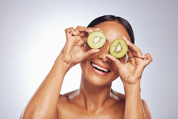 Image showing Skincare, happy and senior woman with kiwi in studio isolated on a white background. Food, natural fruit and face of model with nutrition for wellness, healthy diet or vitamin c, anti aging or beauty