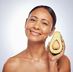 Image showing Face, skincare and senior woman with avocado in studio isolated on a white background. Portrait, natural fruit and happy model with food for organic nutrition, healthy diet and omega 3 for anti aging