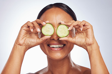 Image showing Cucumber, face and beauty of woman in studio, white background and aesthetic glow. Happy female model, natural skincare and fruits on eyes for sustainable cosmetics, vegan dermatology and nutrition