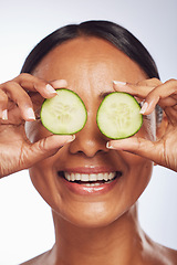 Image showing Cucumber, face and skincare of happy woman in studio, white background and aesthetic shine. Female model, natural beauty and fruits on eyes for sustainable cosmetics, vegan dermatology and nutrition