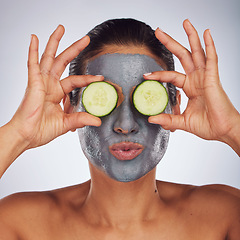 Image showing Eyes, cucumber and mask with a model woman in studio on a gray background for an antiaging facial treatment. Face, skincare and food with a young female person using cosmetic clay on her face