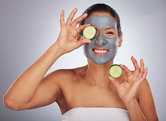 Image showing Portrait, cucumber and mask with a model woman in studio on a gray background for an antiaging facial treatment. Beauty, skincare and fruit with a young female person using cosmetic lay on her face