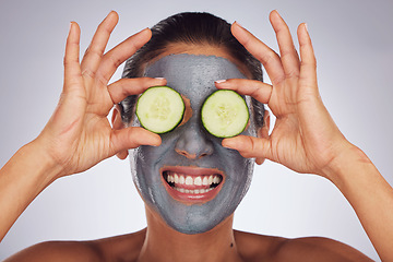 Image showing Facial, cucumber and mask with a model woman in studio on a gray background for an antiaging face treatment. Eyes, skincare and food with a happy young female person using cosmetic clay on her face
