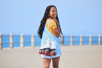 Image showing Portrait, back and roller skating with a black woman by the sea, on the promenade for training or recreation. Beach, sports or fun with a happy young teenager holding skates on the coast by the ocean