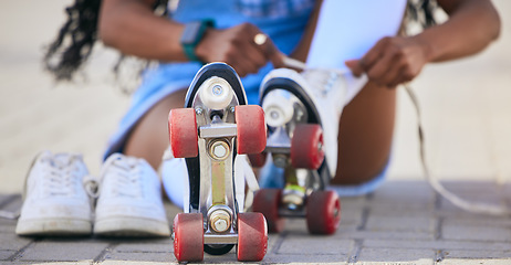 Image showing Roller skates, hands and tie shoes on the ground to start exercise, workout or training outdoor. Skating, person and tying laces to get ready for sports on street to travel, journey and fitness.