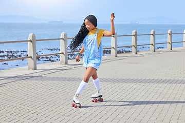 Image showing Roller skating, fun or freedom with a black woman by the sea, on the promenade for training or recreation. Beach, sports and a young female teenager in skates on the coast by the ocean or water