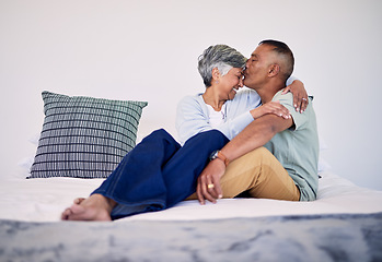 Image showing Love, kiss and senior couple on their bed in their home while relaxing, bonding and spending time together. Happy, affection and elderly man and woman in retirement resting in bedroom in their house.