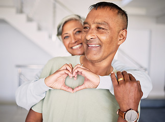 Image showing Heart, hands and couple in home for love, kindness and commitment to life partner, relationship or emoji sign. Mature, man, happy woman and hug with finger shape of care, support or trust in marriage