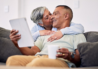 Image showing Senior couple, hug and tablet on sofa to relax with quality time in home with kiss during retirement. Couple, technology and embrace with elderly man or woman in living room together on couch.