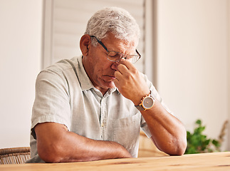 Image showing Stress, headache and old man at table in home with glasses, worry and fatigue in retirement. Debt, anxiety and tired, frustrated senior person with mental health problem or crisis, exhausted and sad.