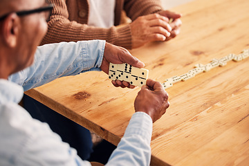 Image showing Hands, dominoes and a senior man playing a game at a table in the living room of a retirement home. Thinking, strategy and fun with an elderly male pensioner in a house closeup for entertainment