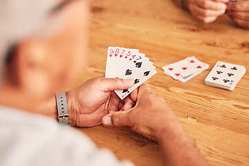 Image showing Hands, cards and a senior man playing poker at a table in the living room of a retirement home. Gambling, planning and fun with an elderly male pensioner in a house closeup for entertainment games