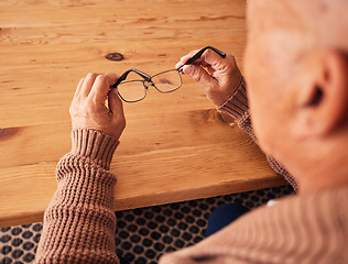 Image showing Senior man, hand holding glasses and eye care with vision, prescription lens and designer frame at table. Elderly guy, hands and spectacles for vision, eyesight and health at desk in retirement home