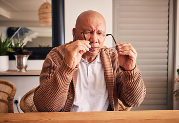 Image showing Glasses, vision and a senior man at a table in the living room of his home during retirement. Thinking, relax and eyesight with an elderly male person holding prescription frame lenses in his house