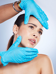 Image showing Woman, plastic surgery and hands on face in studio, check and cosmetics for beauty vision by background. Young girl, model and surgeon gloves with thinking, inspection and measurement for aesthetic