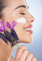 Image showing Woman, face with cream and skincare with flower, natural beauty product with lavender or facial cosmetics in studio background. Skin care, moisturiser and purple flowers for organic cosmetic wellness