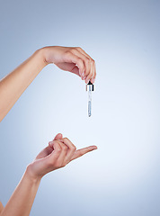 Image showing Skincare, oil serum and hand of woman in studio for wellness, health and product. Dermatology aesthetic, salon and hands with liquid pipette, vial or dropper for moisturizer, cosmetics and beauty