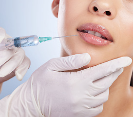 Image showing Lips, botox and plastic surgery with hands on the face of a woman for cosmetic surgery in studio on a blue background. Mouth, filler or beauty and a female patient with her doctor for an injection