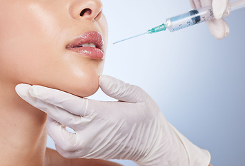 Image showing Mouth, botox and plastic surgery with hands on the face of a woman for cosmetic surgery in studio on a blue background. Lips, filler or beauty and a female patient with her doctor for an injection