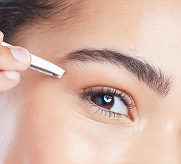 Image showing Closeup of a young woman tweezing her eyebrows in a studio for grooming or hair removal face routine. Skincare, beauty and zoom of female model doing a facial epilation treatment with metal tweezers.