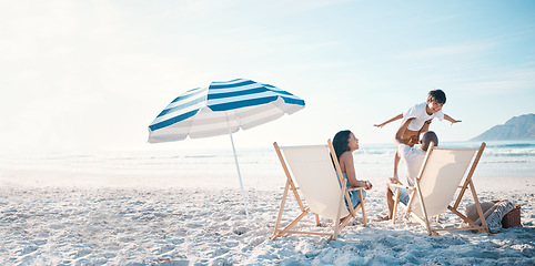 Image showing Beach, travel and family relaxing while on a vacation, adventure or weekend trip for summer. Freedom, bonding and father flying his boy child sitting by the ocean with his wife on a tropical holiday.