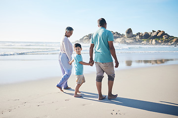 Image showing Beach, walking and grandparents holding hands with child for bonding, quality time and relax in nature. Family, retirement and happy elderly man and woman with boy on holiday, vacation and travel
