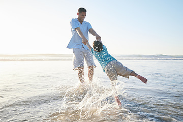 Image showing Beach, family and father and spinning a child for fun, adventure and play on holiday. A man and young kid holding hands on vacation at the ocean, nature or outdoor with water splash and freedom