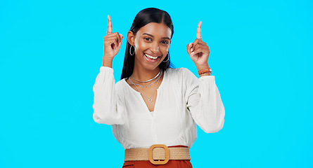 Image showing Excited, happy and woman pointing up at mockup showing deal, sale and branding isolated in a studio blue background. Smile, fashion and portrait of Indian female show product placement or logo