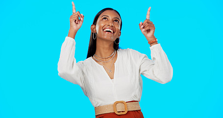 Image showing Excited, happy and woman pointing up at mockup showing deal, sale and branding isolated in a studio blue background. Smile, fashion and portrait of Indian female show product placement or logo