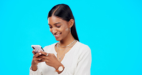 Image showing Phone, typing and young woman isolated on blue background for social media post, networking and chat tech. Happy indian person or online user with mobile app, smartphone or cellphone in studio mockup