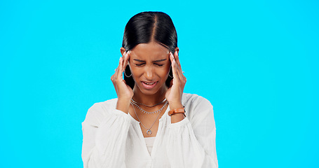 Image showing Woman, headache and studio with hands, migraine and stress on head to massage temple by blue background. Young indian model, pain and anxiety with mental health, fatigue and burnout by backdrop