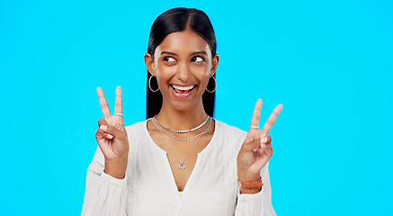 Image showing Happy woman, peace and face wink in studio, blue background and color backdrop. Portrait of female model, v sign and winking of cool girl for victory, smile and fun mood for happiness, emoji or hands