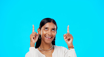 Image showing Mockup, face and Indian woman pointing up, promotion and success on a blue studio background. Portrait, female and lady with gesture for motivation, inspiration and carefree with decision and choice