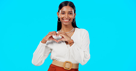 Image showing Happy woman, heart hands and face in studio, blue background and backdrop of care, kindness or emoji. Portrait, female model and finger shape of love, thank you and smile of trust, peace or hope icon