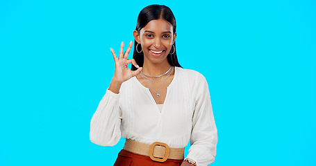 Image showing Ok, perfect and happy woman with hand gesture for success, approval and isolated in studio blue background. Emoji, face and portrait of Indian female with fashion, perfection and support review