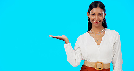 Image showing Woman, studio mockup and open palm with face, fashion and beauty in space by blue background. Happy indian model, gen z girl and hand for product placement, branding or logo in mock up promo portrait