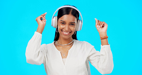 Image showing Face, music and Indian woman with headphones, streaming and happiness against blue studio background. Portrait, female and lady with headset, listening to song and dancing with success and celebrate