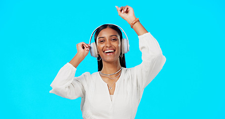 Image showing Face, music and Indian woman with headphones, streaming and happiness against blue studio background. Portrait, female and lady with headset, listening to song and dancing with success and celebrate