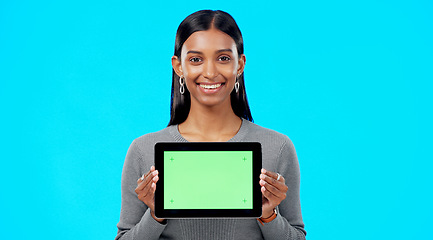 Image showing Mockup, green screen and face of a woman with a tablet isolated on a blue background in a studio. Branding, smile and portrait of an Indian girl holding technology with a blank screen for advertising