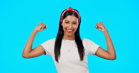 Image showing Flexing, empowerment and woman showing arm muscle, strong and happy person isolated in a studio blue background. Bicep, strength and portrait of an excited female for body positivity