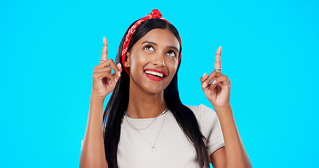 Image showing Face, motivation and Indian woman with decision, pointing and wellness against a blue studio background. Portrait, female and lady with smile, direction and choice with inspiration, promotion and joy