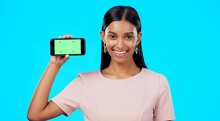 Image showing Chromakey, green screen and portrait of woman holding phone for product place, logo and mobile app advertising. Smile, happy and professional female isolated in a studio blue background