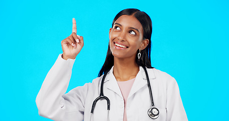 Image showing Healthcare doctor, smile and woman point at medical promotion, hospital notification or clinic announcement mockup. Nurse portrait, studio advertising surgeon and marketing female on blue background