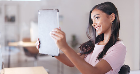 Image showing Young happy woman taking a selfie with a digital tablet while relaxing in an office at work. One smiling female student taking pictures to post on social media while sitting alone in a library