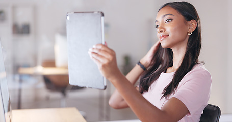 Image showing Young happy woman taking a selfie with a digital tablet while relaxing in an office at work. One smiling female student taking pictures to post on social media while sitting alone in a library